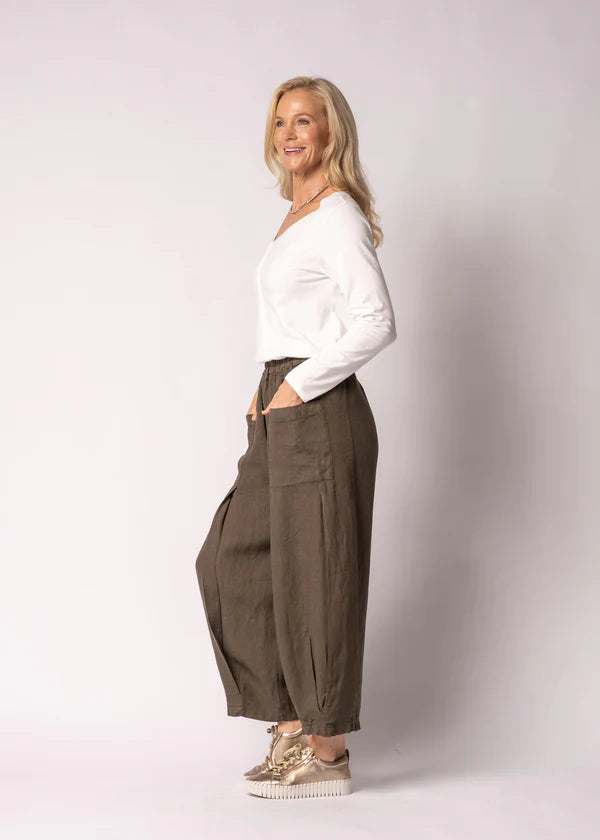 Olenna linen pants in Moss Green, crafted from 100% Italian linen with a full elastic waistband, soft front pleats, post box pockets, and a flowing wide-leg silhouette. Features elegant V-shaped pleat detailing at the hem and a refined, comfortable design for effortless everyday wear.