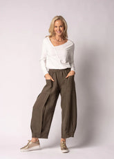 Olenna linen pants in Moss Green, crafted from 100% Italian linen with a full elastic waistband, soft front pleats, post box pockets, and a flowing wide-leg silhouette. Features elegant V-shaped pleat detailing at the hem and a refined, comfortable design for effortless everyday wear.