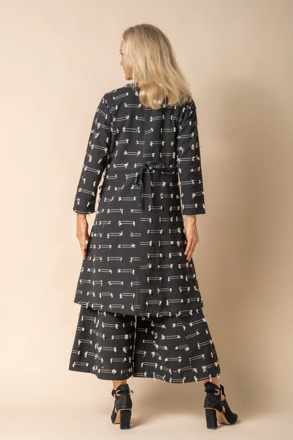 Black cotton jacket with band neckline, wood-look button front, tassel detailing and adjustable drawstring back