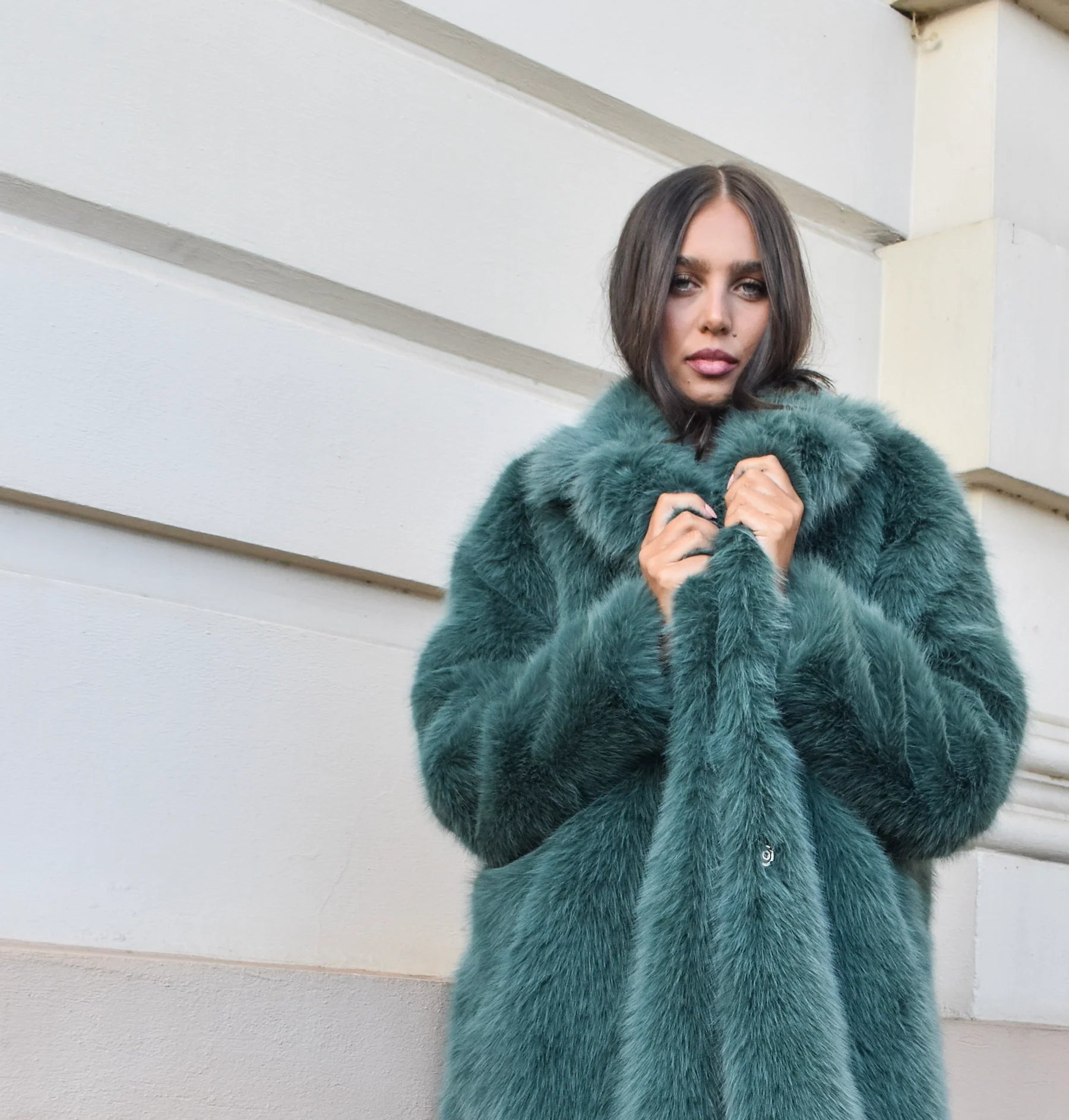Teal green long faux fur coat with collar and two-button closure, featuring a soft plush texture and elegant longline silhouette.