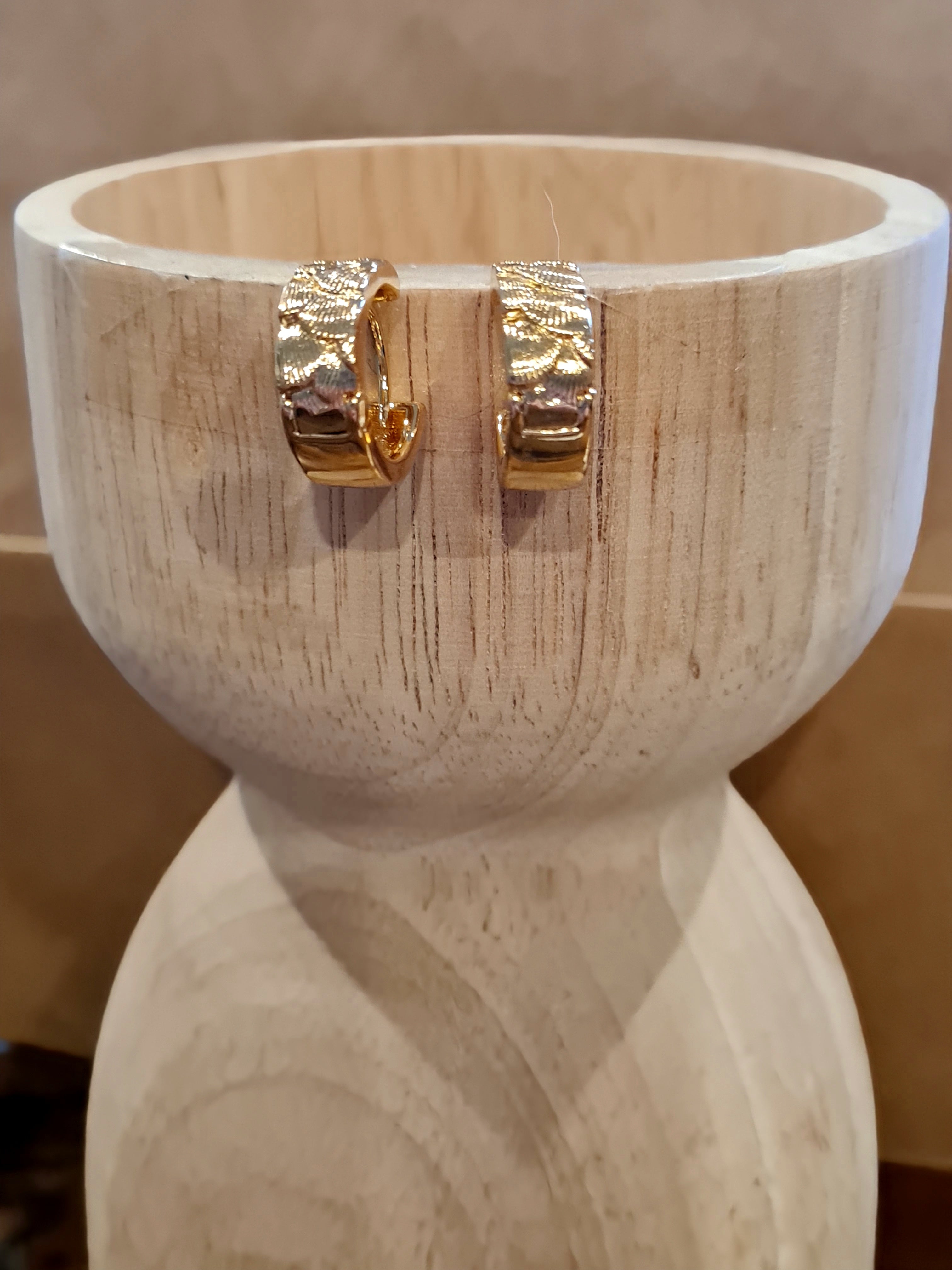 Small huggie hoop earrings with a shell-shaped embossed pattern, available in gold and silver. Check them out at Linens & Treasures