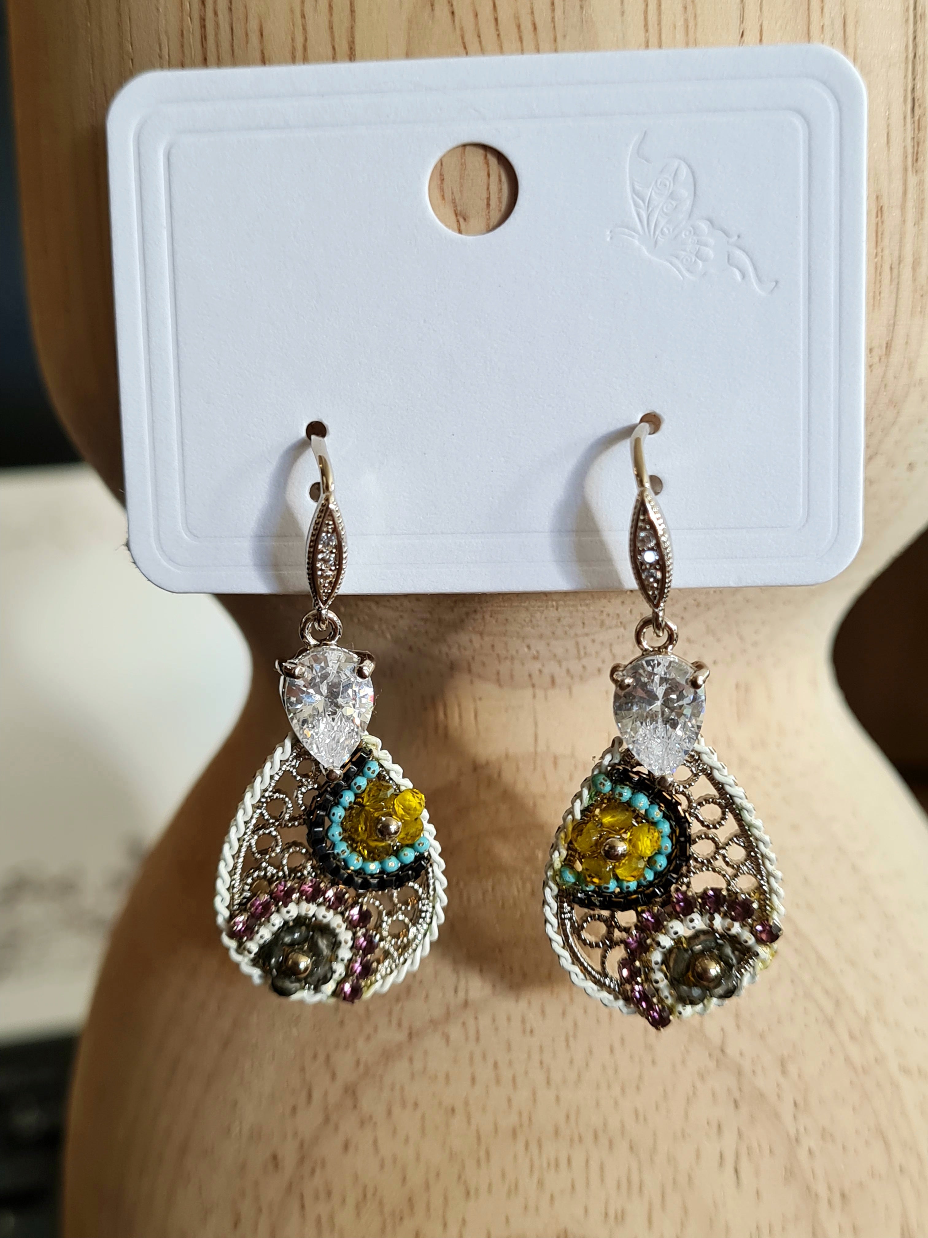 Handmade filigree earrings resembling lace, featuring bead overlay, a crystal-studded top, and a princess-cut crystal drop. See the range at Linens & Treasures
