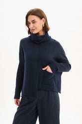 Tirelli Roll Hem Pocket Knit in Navy featuring a relaxed oversized fit, rolled cowl neckline, ribbed sleeves, front patch pocket, exposed centre seam, and asymmetrical roll hem in a classic deep navy knit.