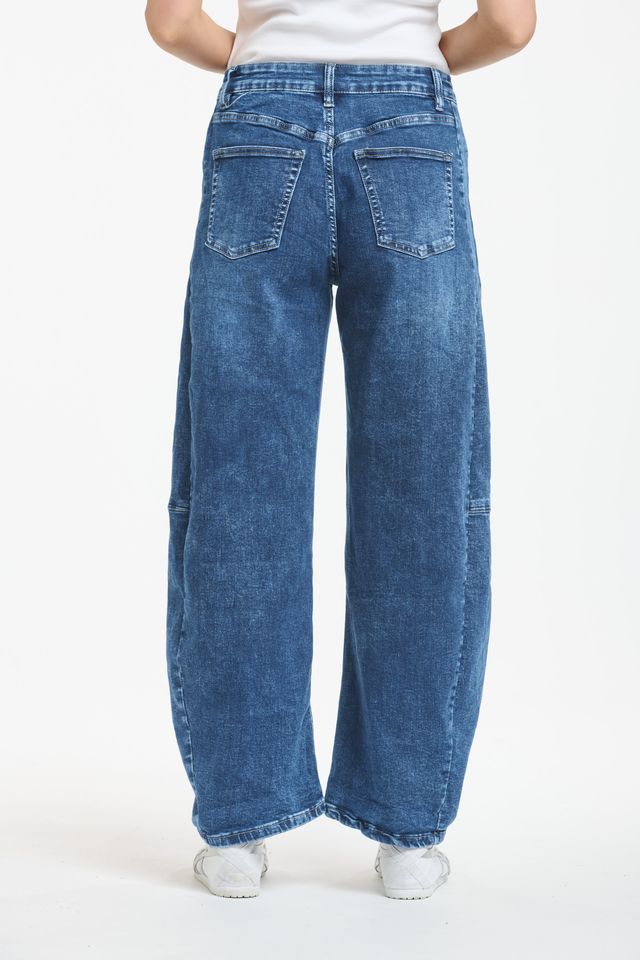 Blue denim barrel leg jeans with curved silhouette and tapered ankle