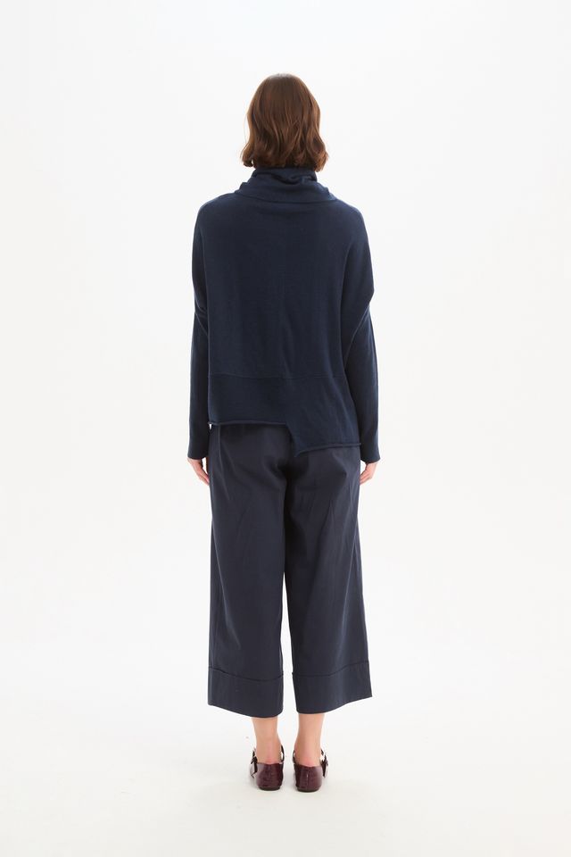 Tirelli Roll Hem Pocket Knit in Navy featuring a relaxed oversized fit, rolled cowl neckline, ribbed sleeves, front patch pocket, exposed centre seam, and asymmetrical roll hem in a classic deep navy knit.