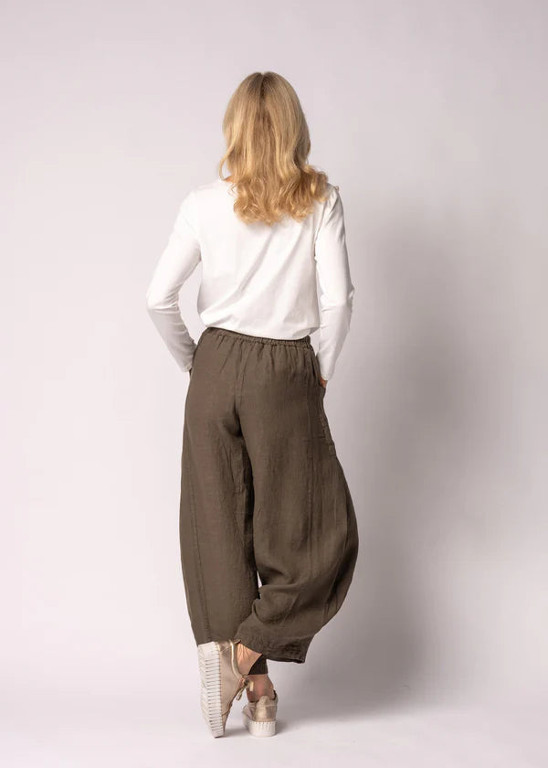 Olenna linen pants in Moss Green, crafted from 100% Italian linen with a full elastic waistband, soft front pleats, post box pockets, and a flowing wide-leg silhouette. Features elegant V-shaped pleat detailing at the hem and a refined, comfortable design for effortless everyday wear.