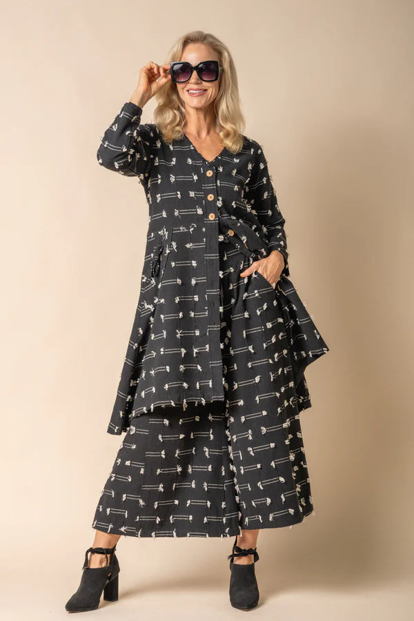 Black cotton jacket with band neckline, wood-look button front, tassel detailing and adjustable drawstring back