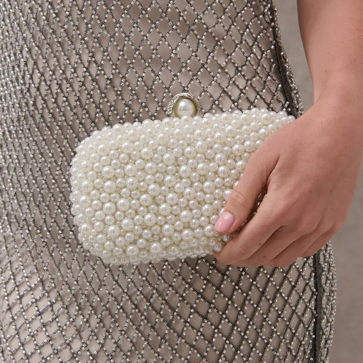 Pearl-encrusted white evening clutch with structured silhouette and pearl clasp detail