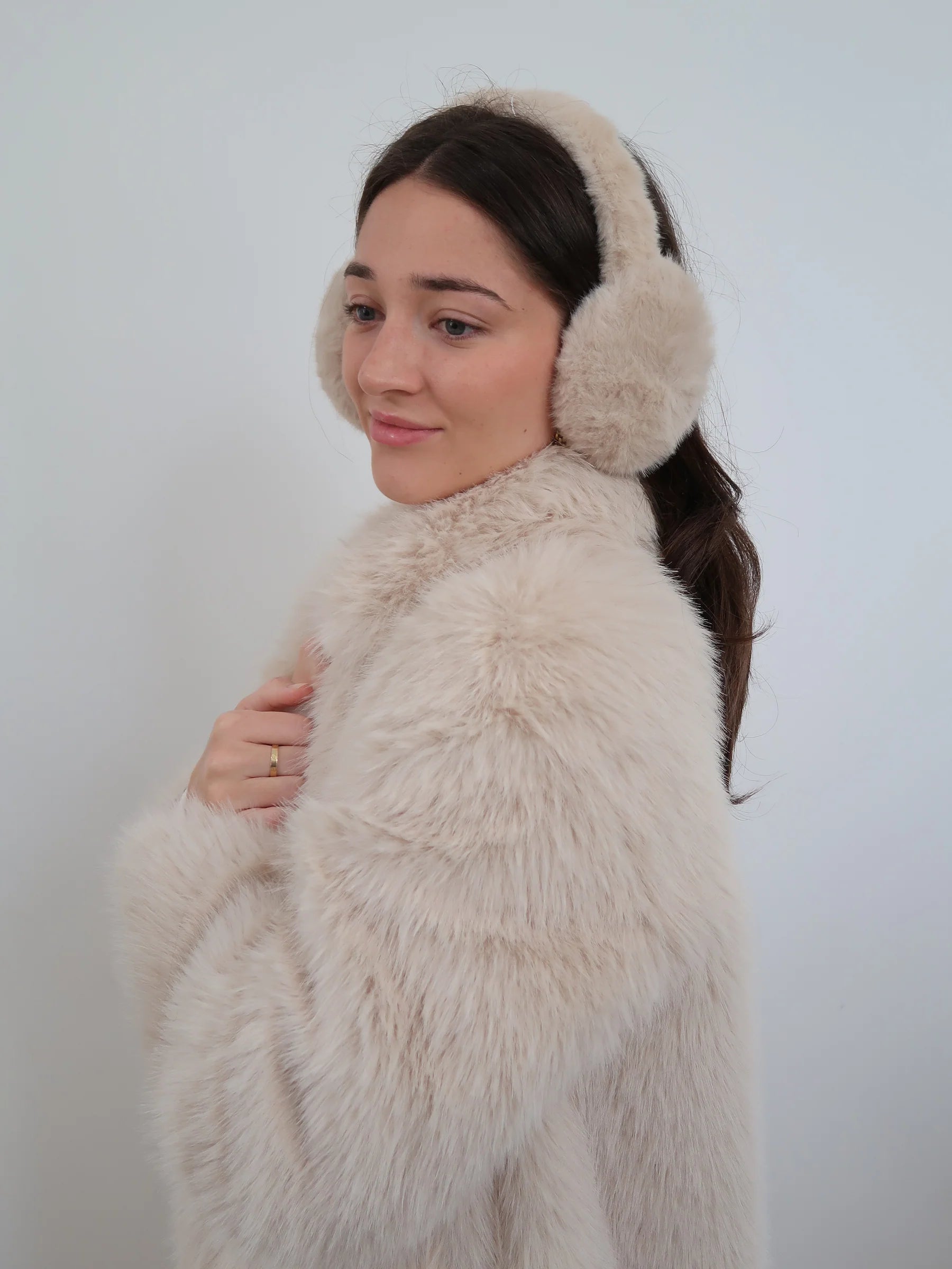 Beige long faux fur coat with soft plush texture, classic collar, and two-button closure in an elegant longline style.