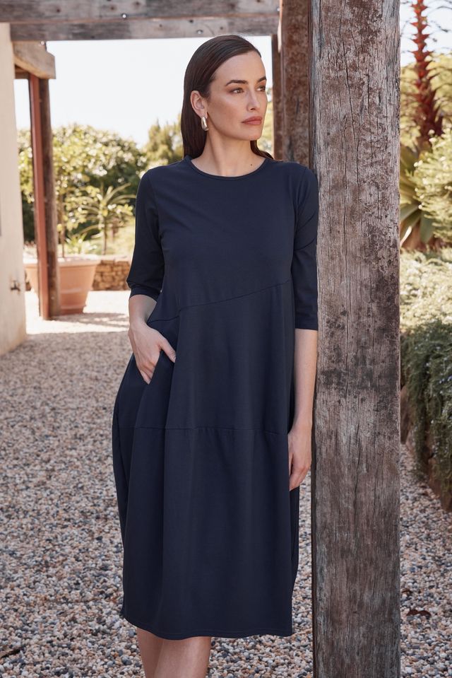 Tirelli Diagonal Seam Winter Dress in navy featuring a midi-length silhouette, diagonal seam detailing, rounded bubble hem, round neckline, and side pockets